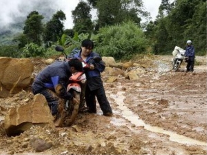 Người và phương tiện gặp khó khăn khi đi qua tuyến tỉnh lộ 129. (Ảnh: Quang Duy/TTXVN)