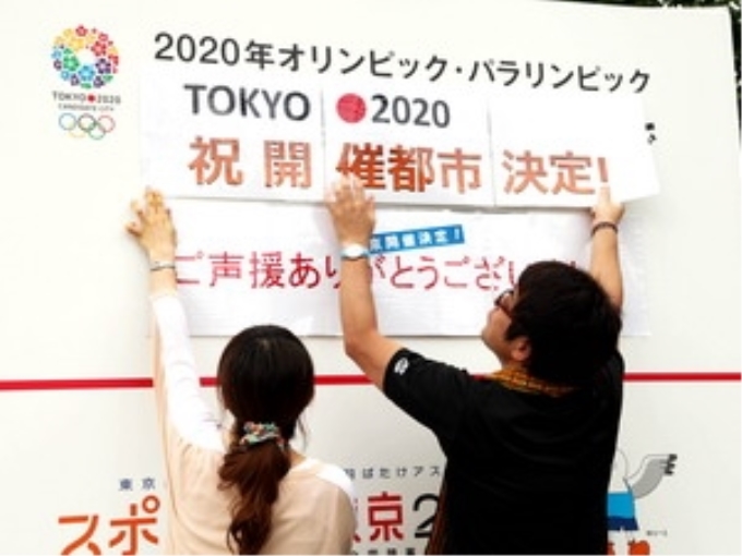 Hai nhân viên Nhà thi đấu thể thao quận Shibuya đang dán panô chào mừng Tokyo là thành phố đăng cai Olympic 2020. (Ảnh: Hữu Thắng/TTXVN)