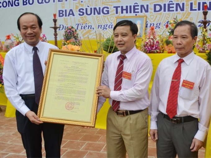 Chủ tịch Ủy ban Nhân dân tỉnh Hà Nam Mai Tiến Dũng (bên trái) trao quyết định công nhận bia Sùng Thiện Diên Linh là bảo vật quốc gia cho lãnh đạo huyện Duy Tiên. (Ảnh: TTXVN)