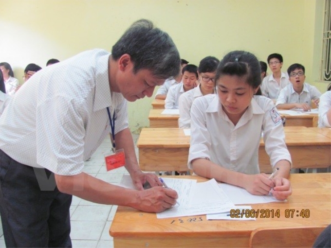 Giám thị ký vào giấy thi cho thí sinh trong kỳ thi tốt nghiệp trung học phổ thông năm 2014. (Ảnh: Phạm Mai/Vietnam+)