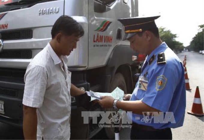 Kiểm tra giấy tờ chủ phương tiện tại trạm cân đường Nguyễn Văn Linh, quận 7, TP Hồ Chí Minh. Ảnh: Hoàng Hải-TTXVN