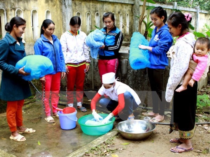 Nhân viên y tế hướng dẫn cách tẩm màn phòng chống bệnh sốt rét cho người dân. (Ảnh: TTXVN)