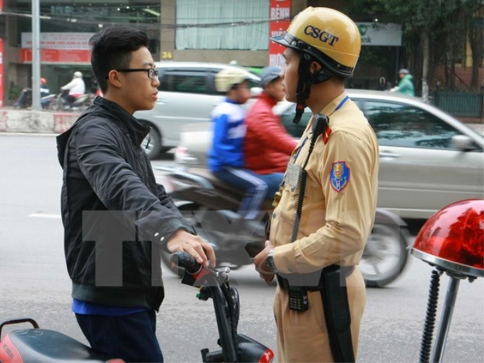 Cảnh sát giao thông đội 4 tiến hành dừng xe, sau đó nhắc nhở học sinh phải đội mũ bảo hiểm khi tham gia giao thông. (Ảnh: Doãn Tấn/TTXVN)