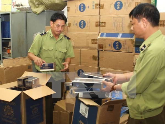 Lực lượng quản lý thị trường Hà Nội kiểm tra lô thuốc lá bị tạm giữ. (Ảnh: Trần Việt/TTXVN)