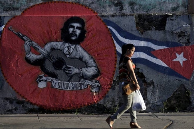 Một phụ nữ đi qua bức graffiti của Che Guevara và lá cờ Cuba trên đường phố thủ đô La Habana. (Nguồn: Reuters)