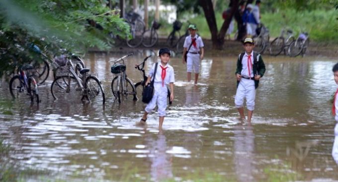 Học sinh Bình Định bì bõm đến trường trong ngày học đầu tiên khi lũ rút - Ảnh: HỮU KHOA