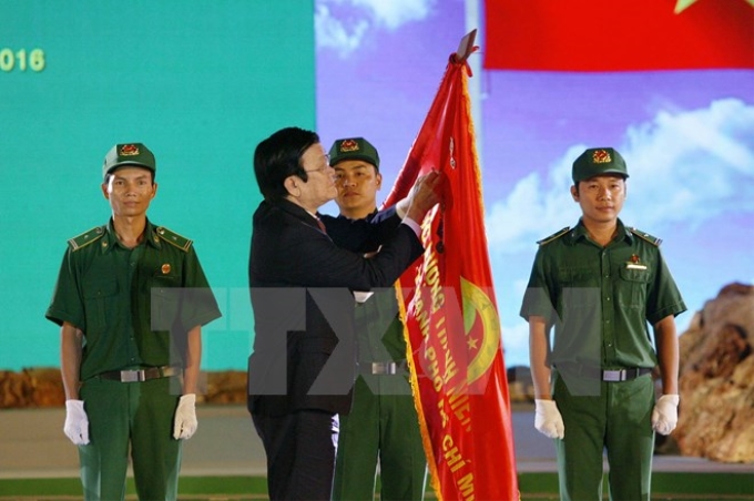 Chủ tịch nước Trương Tấn Sang gắn Huân chương Độc lập hạng Ba lên lá cờ truyền thống của Lực lượng Thanh niên Xung phong TP. HCM. (Ảnh: TTXVN)