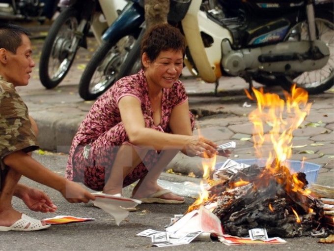 Người dân "hồn nhiên" đốt vàng mã trên đường phố Hà Nội. (Ảnh: TTXVN)