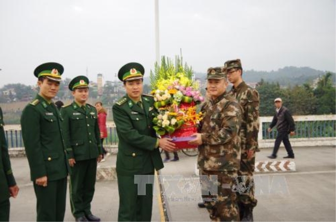 Thượng tá Nguyễn Văn Tuấn (bên trái), Chính trị viên Đồn Biên phòng Cửa khẩu quốc tế Lào Cai tặng hoa cho đại đội công an biên phòng huyện Hà Khẩu, Trung Quốc. Ảnh: Hồng Ninh/TTXVN