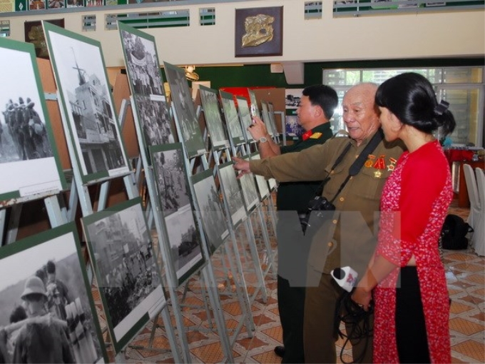 Nghệ sỹ nhiếp ảnh Minh Lộc - giữa - giới thiệu về các tác phẩm của mình tại triển lãm. (Ảnh: Mạnh Linh/TTXVN)