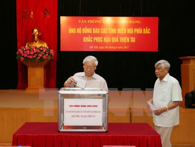 Tổng Bí thư Nguyễn Phú Trọng, nguyên Tổng Bí thư Lê Khả Phiêu tham gia quyên góp ủng hộ đồng bào các tỉnh miền núi phía Bắc. (Ảnh: Trí Dũng/TTXVN)