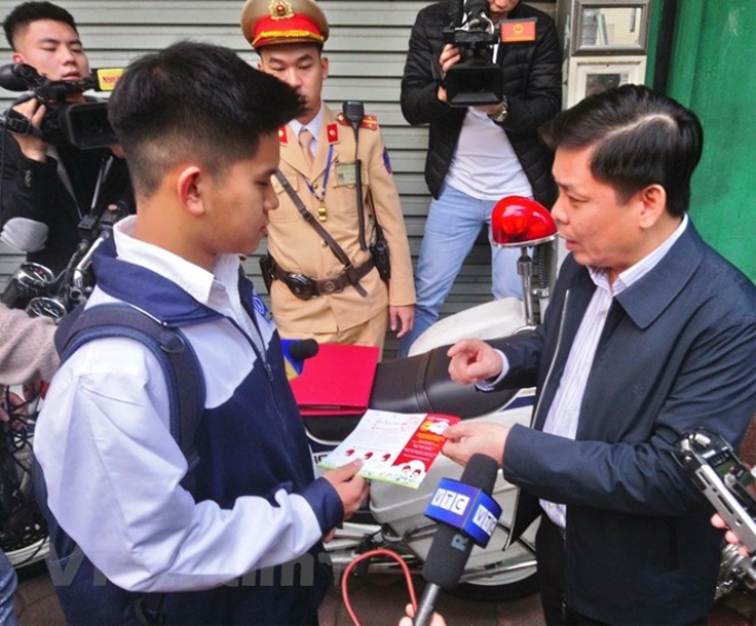 Bộ trưởng Nguyễn Văn Thể tặng phiếu mua mũ bảo hiểm cho học sinh. (Ảnh: Việt Hùng/Vietnam+)