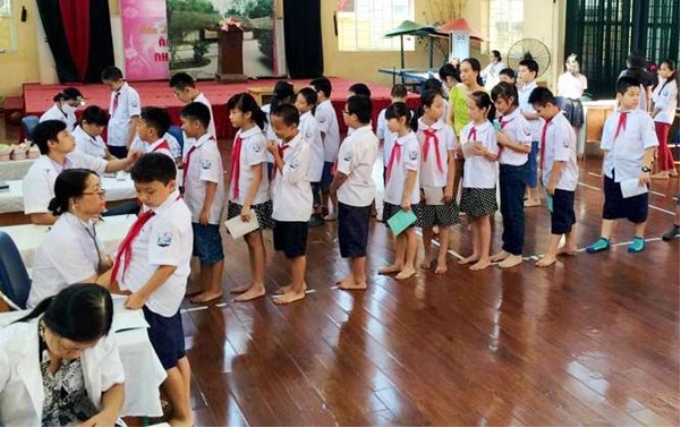 Cán bộ y tế quận Hoàng Mai phối hợp cùng các cán bộ y tế trên địa bàn khám sức khỏe định kỳ cho học sinh.(Nguồn: VGP)