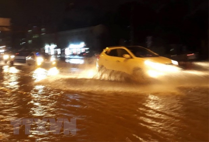 Các phương tiện di chuyển trên mặt đường Phạm Văn Đồng, quận Cầu Giấy bị ngập nước tối 15/7. (Ảnh: Văn Điệp/TTXVN)