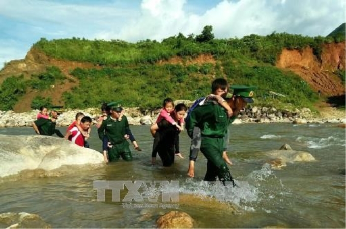 Các chiến sĩ Đồn Biên phòng Sin Suối Hồ (huyện Phong Thổ, tỉnh Lai Châu) cõng học sinh qua suối chảy xiết về trường học. (Ảnh: TTXVN)