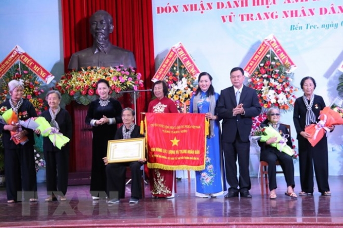 Chủ tịch Quốc hội Nguyễn Thị Kim Ngân trao danh hiệu Anh hùng Lực lượng vũ trang nhân dân cho Hội Phụ nữ giải phóng - Đội quân tóc dài thời kỳ Đồng khởi của tỉnh Bến Tre. (Ảnh: TTXVN)