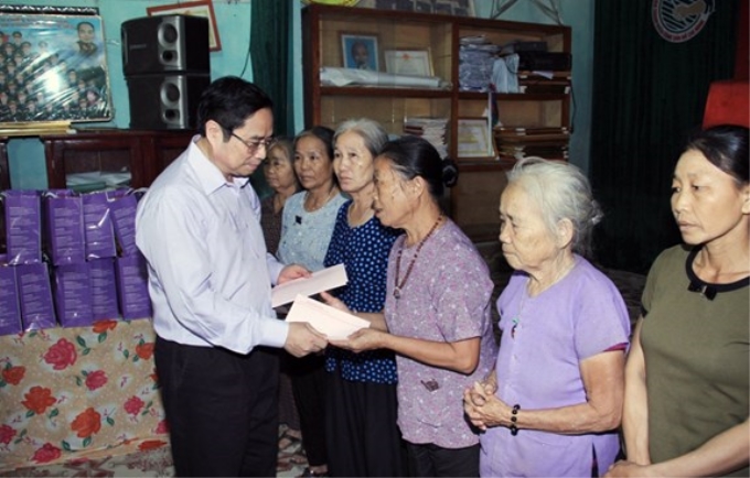 Đồng chí Phạm Minh Chính trao quà tặng người dân ở huyện Cẩm Thủy.