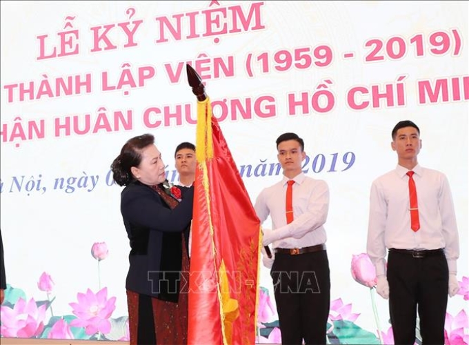 Chủ tịch Quốc hội Nguyễn Thị Kim Ngân gắn Huân chương Hồ Chí Minh lên cờ truyền thống của Viện khoa học Thủy lợi Việt Nam. Ảnh: Trọng Đức/TTXVN