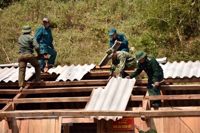 Cán bộ, chiến sỹ đồn biên phòng cửa khẩu Lóng Sập giúp người dân sửa lại nhà. (Ảnh: Hữu Quyết/TTXVN)