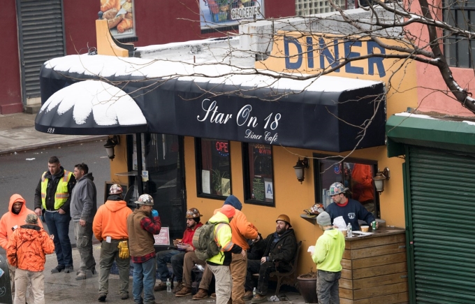 Các công nhân xây dựng trong giờ nghỉ giải lao tại một quán càphê ở New York, Mỹ. (Ảnh: AFP/TTXVN)