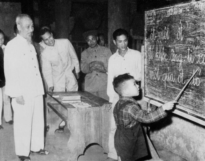 Chủ tịch Hồ Chí Minh quan sát một cháu thiếu nhi tập đánh vần khi đến thăm lớp vỡ lòng Đình Thạch Khối ở phố Hàng Than, Hà Nội (31/12/1959). (Nguồn: TTXVN)