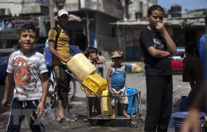 Trẻ em Palestine xếp hàng lấy nước sinh hoạt tại thành phố Gaza. (Ảnh: AFP/TTXVN)