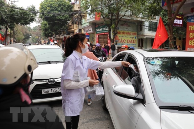 Nhân viên một cửa hàng thuốc tại Ninh Bình phát khẩu trang y tế miễn phí cho người dân. (Ảnh minh họa: TTXVN)