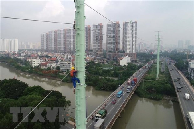 Công nhân Tổng Công ty Điện lực Thành phố Hồ Chí Minh thi công trồng trụ điện trên đường Đồng Văn Cống. (Ảnh: TTXVN)