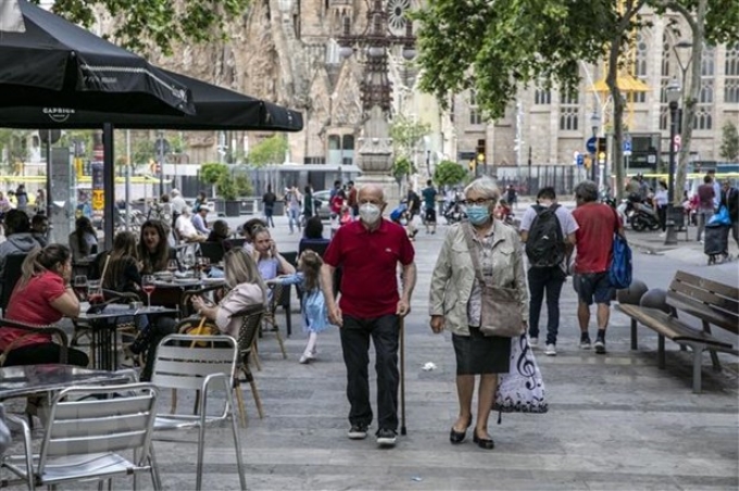 Người dân đeo khẩu trang phòng tránh COVID-19 tại một khu phố ở Barcelona, Tây Ban Nha. (Nguồn: THX/TTXVN)