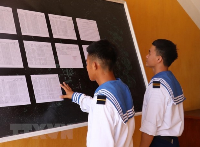Hai chiến sỹ trẻ lần đầu tiên được đi bầu, theo dõi danh sách cử tri được niêm yết tại Ủy ban Nhân dân xã Song Tử Tây (huyện Trường Sa, tỉnh Khánh Hoà). (Ảnh: Sỹ Tuyên/TTXVN)