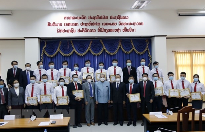 Phó Thủ tướng Lào Kikeo Khaykhamphithoune (giữa) cùng các quan chức chụp ảnh lưu niệm với Đoàn chuyên gia y tế Việt Nam. (Ảnh: TTXVN)