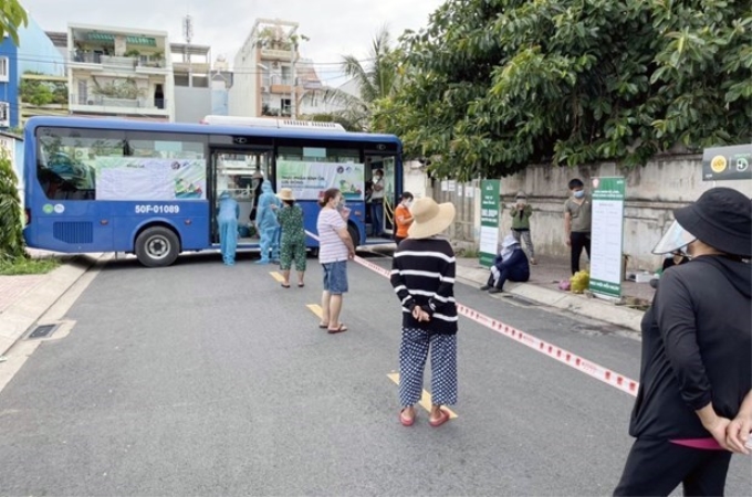 Người dân Thành phố Hồ Chí Minh xếp hàng mua sắm tại xe buýt bán hàng bình ổn. (Ảnh: TTXVN)