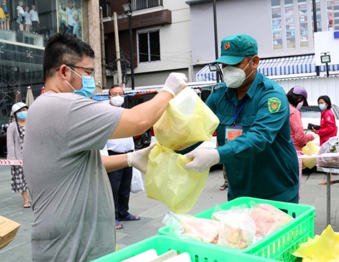 Lực lượng chức năng phường 12, quận 3 hỗ trợ người dân mua hàng hóa, thực phẩm các loại và trứng tại điểm xe bán hàng lưu động của Sở Công thương thành phố.