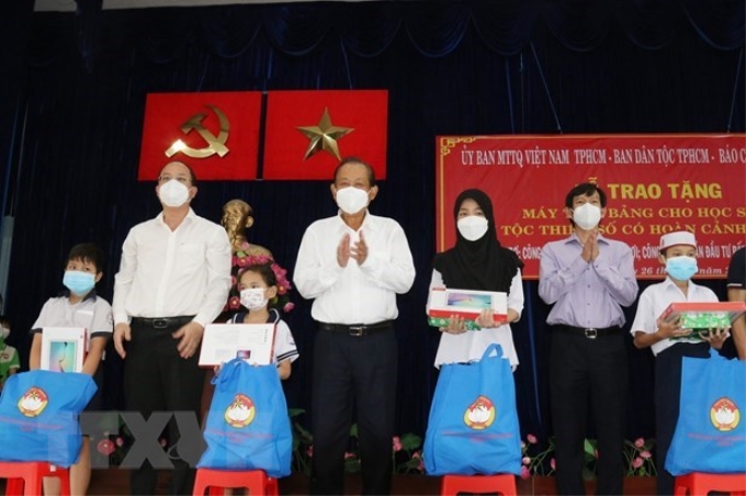 Ông Trương Hòa Bình, nguyên Ủy viên Bộ Chính trị, nguyên Phó Thủ tướng Thường trực Chính phủ và ông Nguyễn Hồ Hải, Phó Bí thư Thành ủy Thành phố Hồ Chí Minh (thứ 2 từ trái sang) trao tặng máy tính bảng cho các học sinh dân tộc Chăm và Khmer. (Ảnh: TTXVN)