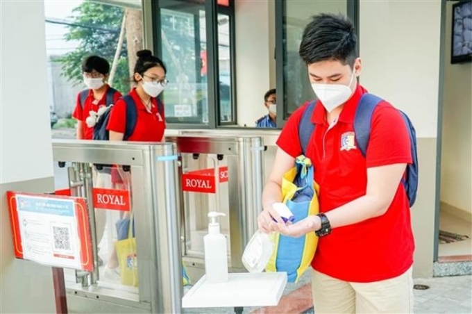 Học sinh trường Song ngữ Quốc tế Hoàng gia (quận 7) khử khuẩn tay trước khi vào trường. (Ảnh: TTXVN phát)