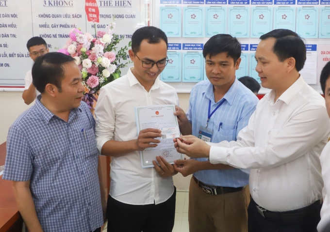 Phó Tổng giám đốc BHXH Việt Nam Chu Mạnh Sinh trao thẻ bảo hiểm y tế của bé gái cho anh Đinh Tiến Hoàng bố cháu bé