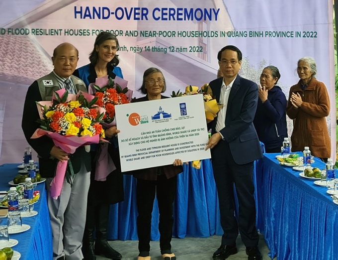 Đồng chí Phó Chủ tịch UBND Phan Mạnh Hùng và đại diện UNDP, tổ chức World Share tặng hoa chúc mừng các hỗ dân được hỗ trợ xây nhà tại xã Tân Ninh.
