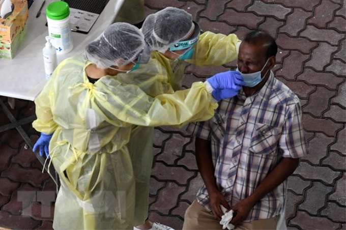 Nhân viên y tế lấy mẫu xét nghiệm COVID-19 cho người dân tại Singapore. (Ảnh: AFP/TTXVN)