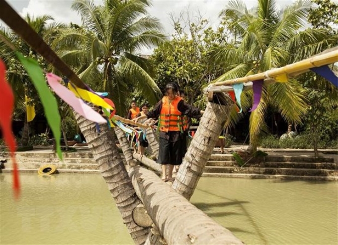 Du khách trải nghiệm đi cầu dừa trên vùng sông nước Bến Tre trong Khu du lịch sinh thái Lan Vương, ấp 2, xã Phú Nhuận, thành phố Bến Tre (Bến Tre). (Ảnh: Hồng Đạt/TTXVN)