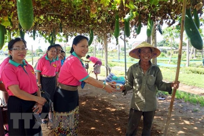 Đại biểu Hội Liên hiệp Phụ nữ Lào tặng biểu tượng hoa Champa cho một người dân làng trồng rau truyền thống Trà Quế, thành phố Hội An, tỉnh Quảng Nam. (Ảnh: Trịnh Bang Nhiệm/TTXVN)