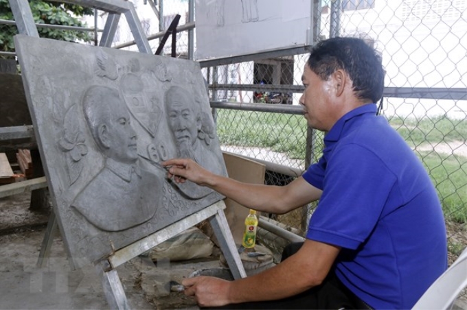 Anh Khanpan Vilaphan, Phó Trưởng khoa Điêu khắc, Học viện Mỹ thuật Lào, hoàn thành bức phù điêu. (Ảnh: Phạm Kiên/TTXVN)