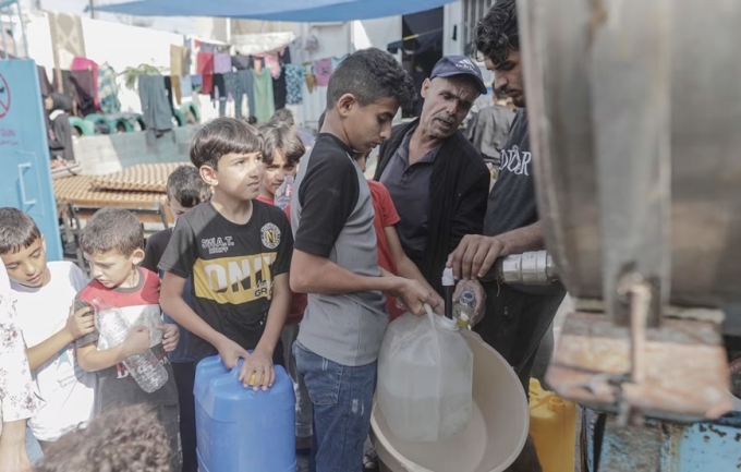 Người dân xếp hàng lấy nước ngọt tại một điểm ở thành phố Khan Younis, phía Nam dải Gaza. (Ảnh: EPA)