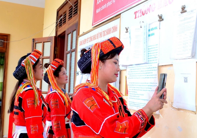 Người dân dễ dàng được hướng dẫn thực hiện DVC trực tuyến khi dùng điện thoại thông minh quét mã QR dán tại Bộ phận tiếp nhận và trả kết quả giải quyết TTHC xã Linh Phú, huyện Chiêm Hóa. Ảnh: Lý Thịnh