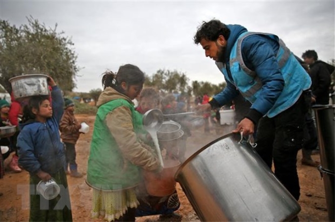 Trẻ em xếp hàng nhận bữa ăn từ thiện tại tỉnh Aleppo, Syria. (Ảnh: AFP/TTXVN)