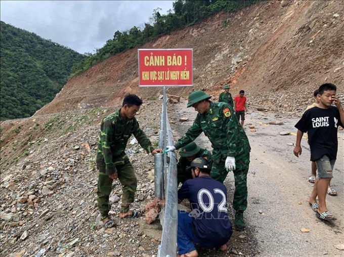 Chính quyền địa phương, lực lượng bộ đội biên phòng khắc phục các điểm sạt lở, đặt biển báo tại các vị trí nguy hiểm trên tuyến đường tỉnh 543D. Ảnh: TTXVN phát