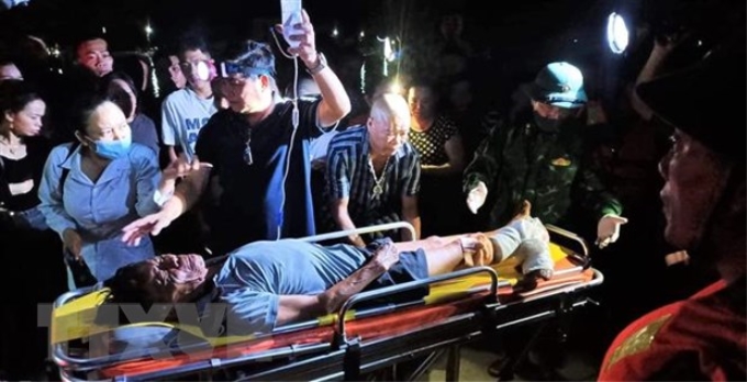 Ngư dân Nguyễn Ngọc được các lực lượng và gia đình hỗ trợ đưa đi bệnh viện cấp cứu, điều trị. (Ảnh: TTXVN)