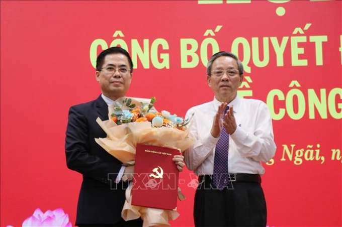 Phó Trưởng ban Tổ chức Trung ương Hoàng Đăng Quang trao Quyết định và tặng hoa chúc mừng đồng chí Nguyễn Hoàng Giang. (Ảnh: TTXVN)