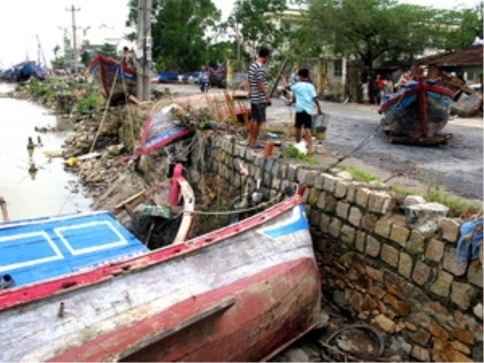 Tàu thuyền bị lũ, gió đánh bật lên trên đường. (Ảnh: Thế Lập/TTXVN)